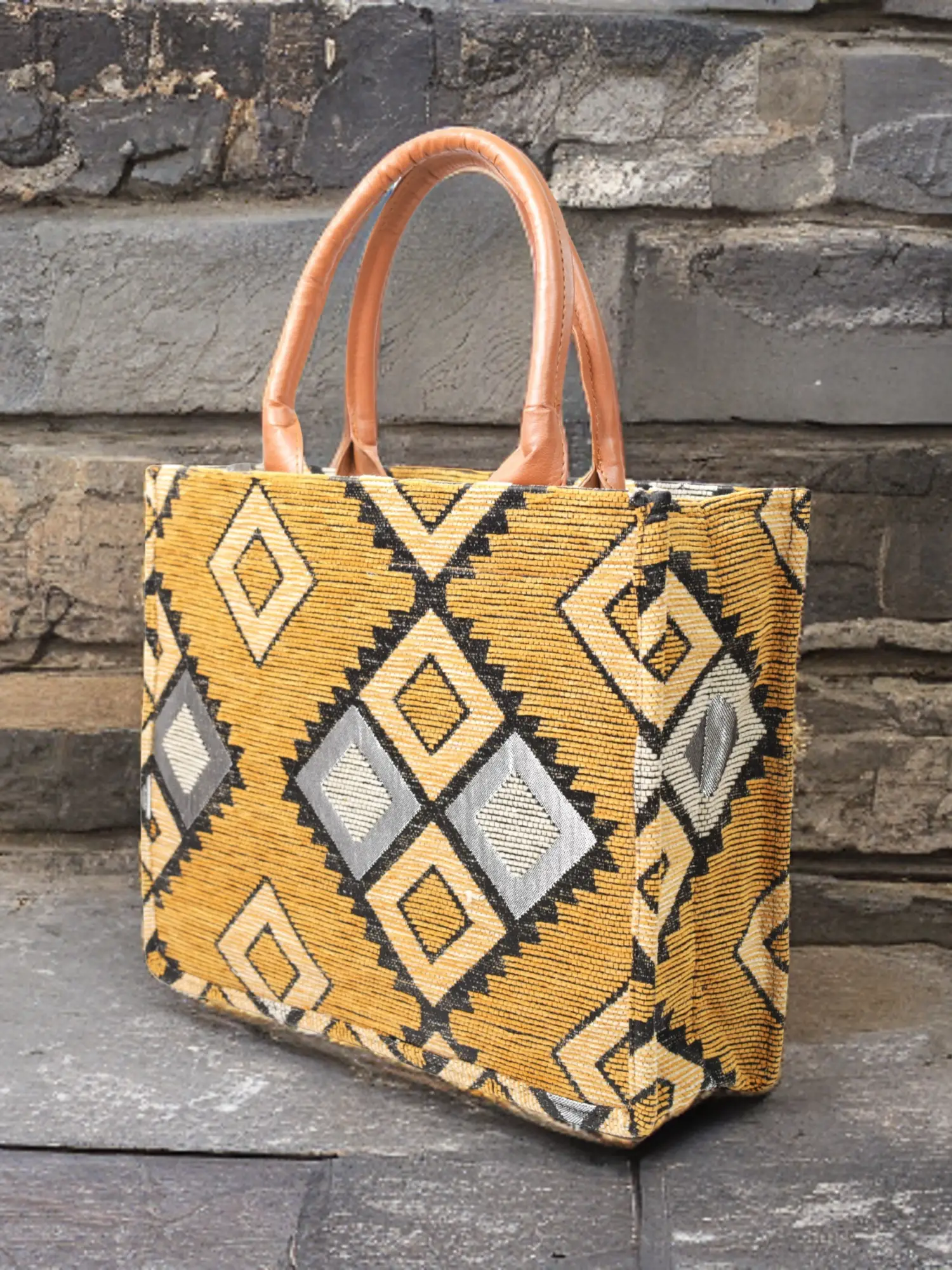 Berber pattern handbag with intricate colorful shapes ,featuring sturdy top handles and a black suede interior